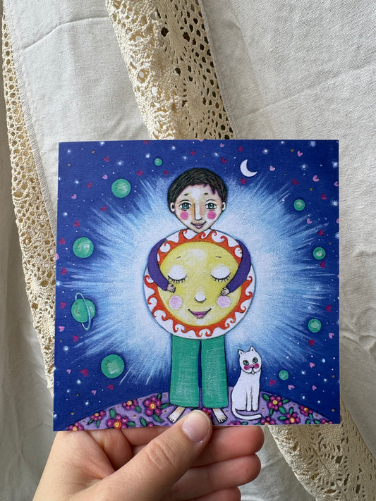 Shine greeting card: hand-painted illustration of a boy hugging a glowing sun against a starry night sky, with planets, a crescent moon and a white cat, from What Makes Your Heart Sing